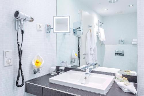 a white bathroom with a sink and a shower at Best Western Macrander Hotel Frankfurt/Kaiserlei in Offenbach