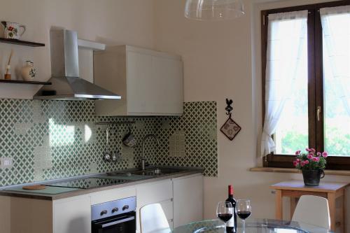 a kitchen with white cabinets and a table with wine glasses at Le Case in Bevagna