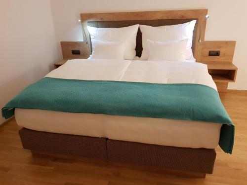 ゼーボーデンにあるSPA-Loungeのベッド(白いシーツ、緑の毛布付)