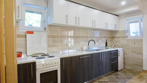 une cuisine avec des armoires blanches, un évier et une cuisinière dans l'établissement Apartman Spirto, à Trebinje