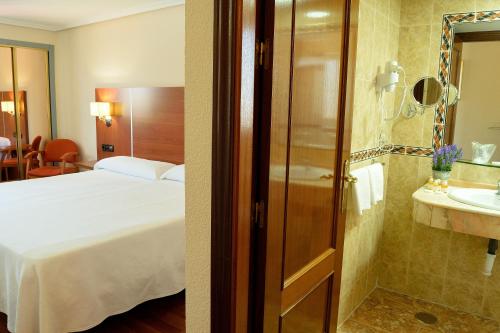 2 fotos de una habitación de hotel con cama y baño en Hotel Mari Carmen, en Guadix