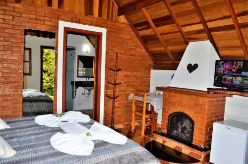 two beds in a room with a brick fireplace at Chalés Fazenda das Samambaias in Monte Verde