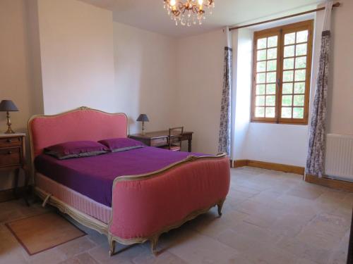 - une chambre avec un lit rose et une fenêtre dans l'établissement le presbytère de Montaigut, à Montégut