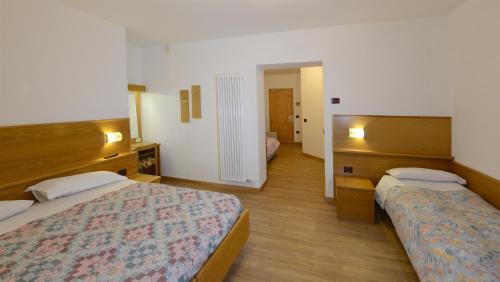 パッソ・デル・トナーレにあるHotel Stellaのベッド2台と鏡が備わるホテルルームです。