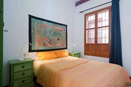 グラナダにあるSpacious, sunny and quiet Albayzin apartmentのベッドルーム1室(壁に絵画が描かれたベッド1台付)