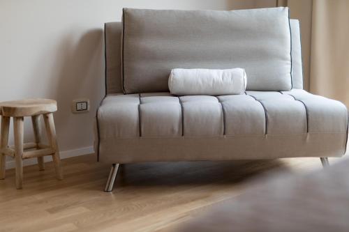 a couch sitting in a living room with a stool at Love & Fama Hotel in Sabaudia