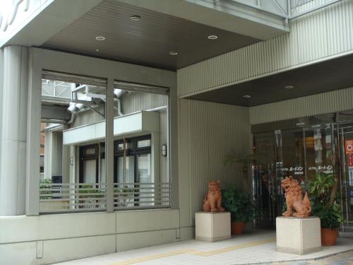 dos estatuas de gatos sentados fuera de un edificio en Hotel Route-Inn Naha Asahibashi Eki Higashi, en Naha