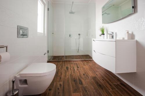 a white bathroom with a toilet and a shower at Villa Dora in Sužan