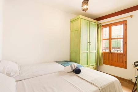 1 dormitorio con cama blanca y armario verde en Luminous Alhambra view apartment in Albayzín, en Granada