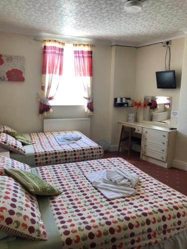 a bedroom with two beds and a desk and a sink at Hotel Athol Blackpool in Blackpool