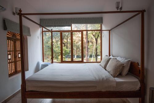 a bedroom with a four poster bed with a window at Botanique Goa in Assagao
