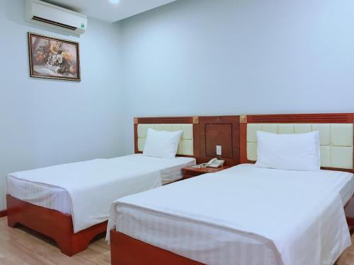 two beds in a room with white sheets at Hoang Ngoc Hotel in Pleiku