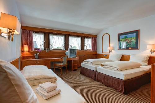 a hotel room with two beds and a desk at Hotel Stern by EMPA in Ulm
