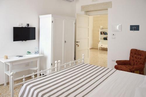 a white bedroom with a bed and a chair at B&B PALAZZO MARZO in Otranto