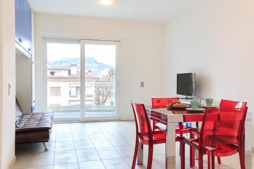 a dining room with red chairs and a table with a television at Prestige Apartments by Quokka 360 - spacious flats with terraces in Lugano