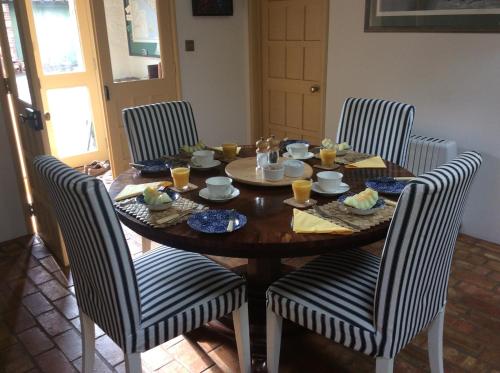 een houten tafel met vier stoelen eromheen met eten erop bij Top Parts Bed & Breakfast in Abbotsbury