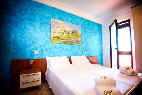 1 dormitorio con 2 camas y pared azul en B&B NiloSira, en Morciano di Leuca