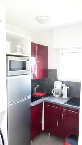 La cuisine est équipée de placards rouges et d'un réfrigérateur en acier inoxydable. dans l'établissement Appart Bord De Mer Dinard, à Dinard