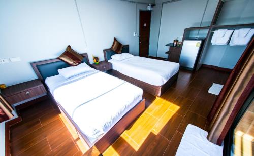 two beds in a room with wooden floors at Na Siri Lake View in Samut Prakan