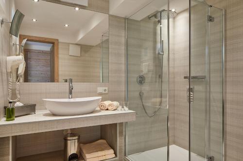 a bathroom with a sink and a glass shower at Dolomit Boutique Hotel in La Villa