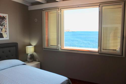 a bedroom with a bed and a view of the ocean at Nettuno Suite in Siracusa