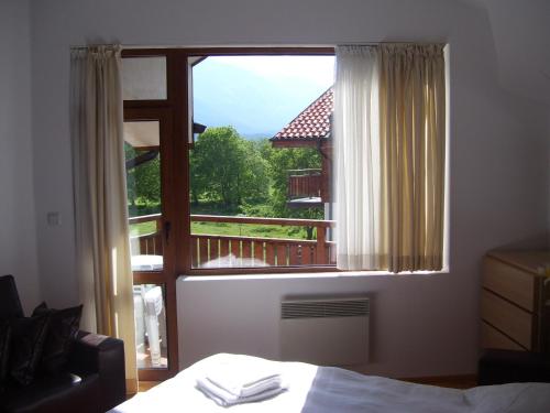 a bedroom with a window with a view of a balcony at Apartments Four Leaf Clover Bansko to rent in Bansko