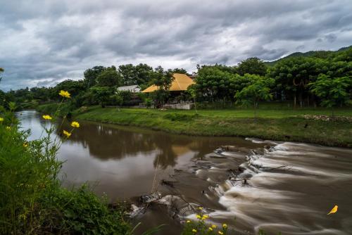a river with a house in the background at Canary Guesthouse in Pai