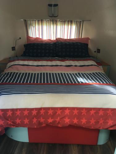 ein Bett mit roten Sternen auf einem Zimmer in der Unterkunft Ludlow Vintage Airstream in Ludlow