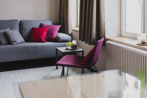 a living room with a purple couch and pink pillows at Hotel Villa Bodeblick in Schierke