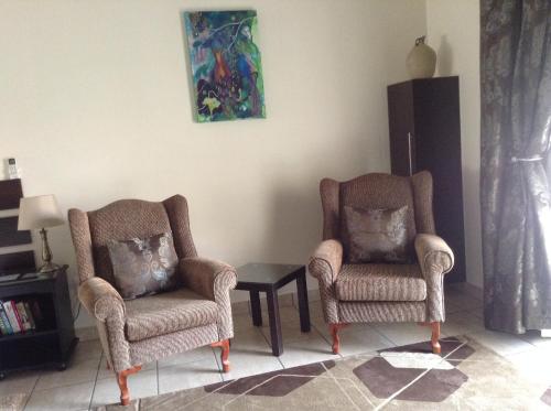 two chairs and a table in a living room at Welcome Guest House in Vereeniging