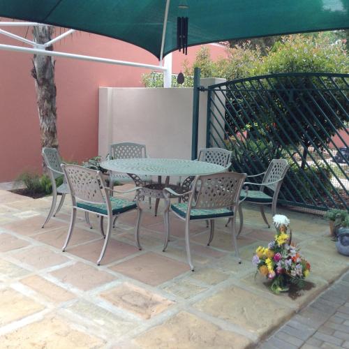 a patio with a table and chairs and an umbrella at Welcome Guest House in Vereeniging