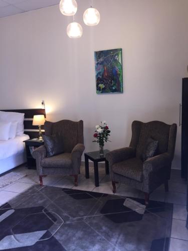 a hotel room with two chairs and a bed at Welcome Guest House in Vereeniging