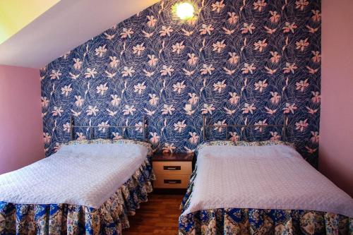 two beds in a room with a floral wallpaper at Osobyi Guest house in Cholpon-Ata