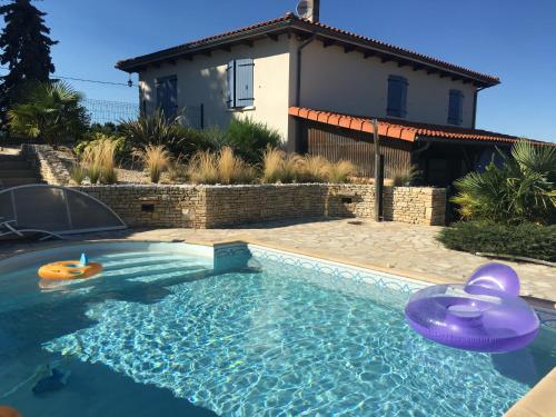 a swimming pool with inflatable toys in front of a house at La Ligonne in Marillac