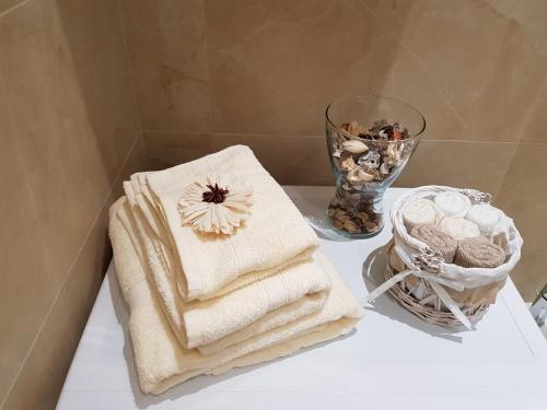 a bathroom counter with towels and a vase with shells at L&G's Roof Terrace in Pisa