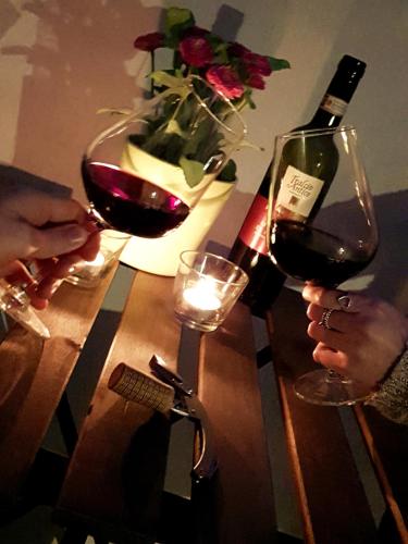 two people holding glasses of wine on a wooden table at L&G's Roof Terrace in Pisa
