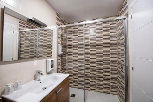 a bathroom with a sink and a glass shower at Apartamentos VIDA Mar de Laxe in Laxe