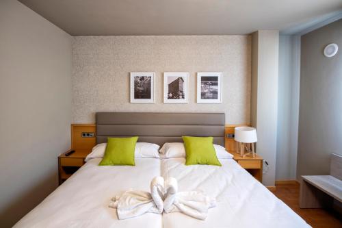 1 dormitorio con 1 cama blanca grande con almohadas verdes en Hotel VIDA Mar de Laxe, en Laxe