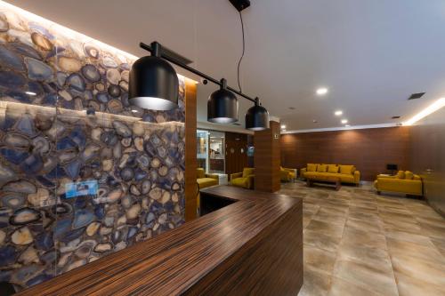 a lobby with a stone wall and yellow chairs at Hotel VIDA Mar de Laxe in Laxe