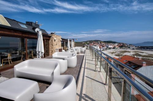 a balcony with white chairs and an ocean view at Hotel VIDA Mar de Laxe in Laxe