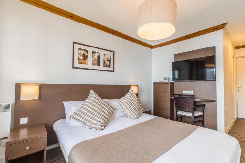 a bedroom with a bed and a desk and a television at Madame Vacances Hôtel & Spa Le Mottaret in Méribel