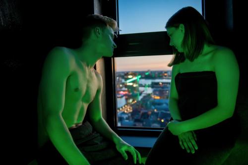 a man and a woman standing in front of a window at Exclusieve privé wellness penthouse SkyNooz in Antwerp