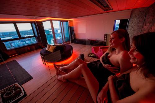 two women sitting on a couch in a living room at Exclusieve privé wellness penthouse SkyNooz in Antwerp