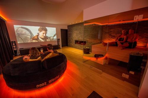 a group of people sitting in a living room watching a movie at Exclusieve privé wellness penthouse SkyNooz in Antwerp