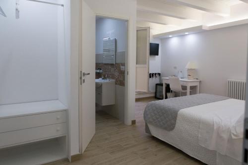 a white bedroom with a bed and a bathroom at Vento di Sicilia in Siracusa