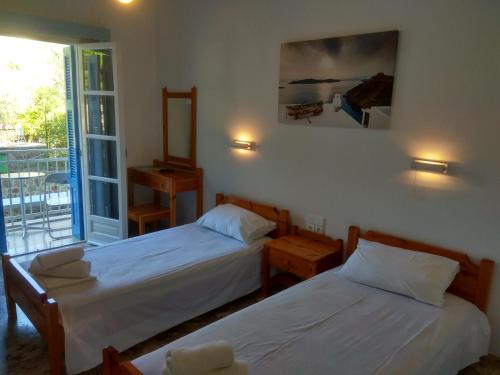 a bedroom with two beds and a balcony at Panos Studios in Poros