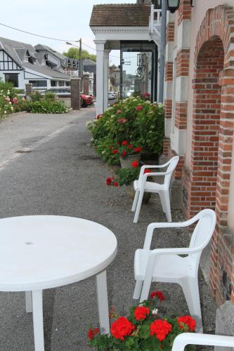 two white tables and chairs next to a building with flowers at Hotel Royal Albion in Mesnil-Val-Plage