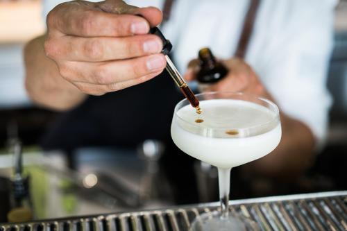 a bartender is stirring a drink in a martini glass at FREIgeist Göttingen Innenstadt, A Member of Design Hotels in Göttingen