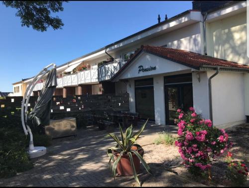 a building with a patio with flowers and an umbrella at Pension " Zu den Linden" Trin in Trinwillershagen