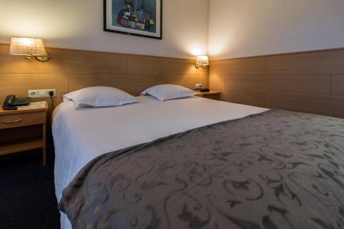a large bed in a hotel room with two pillows at Hotel Edenpark in Brunssum